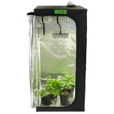 Black BAUX hydroponic grow tent kit, reflective interior, LED light, ventilation system, and green potted plants.