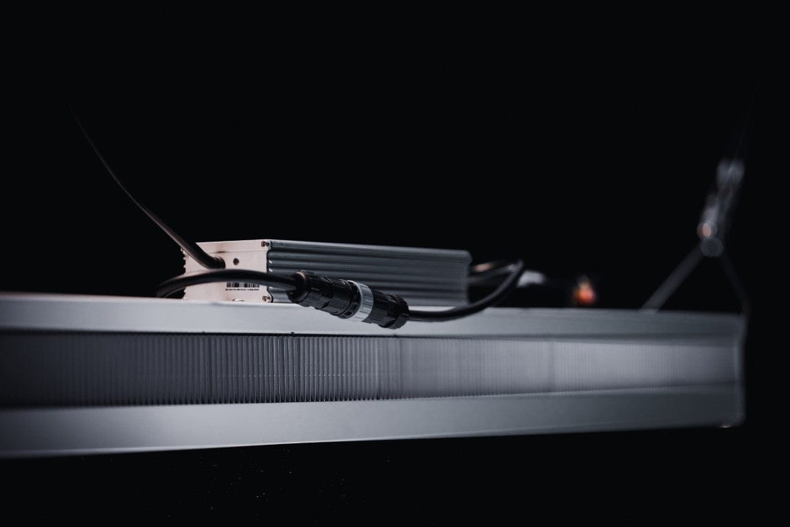 Close-up of a grey LED grow light with black cables and a silver heatsink.