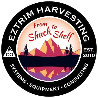 EZTRIM HARVESTING logo. Black circle, mountains, trees, water, 'From Shuck to Shelf', 'Systems • Equipment • Consulting', EST. 2010.