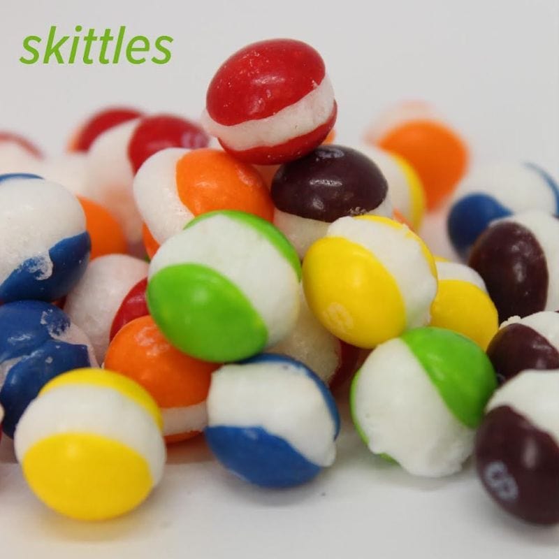 Heap of colorful, puffy freeze-dried Skittles candies, striped with white and various vibrant colors.