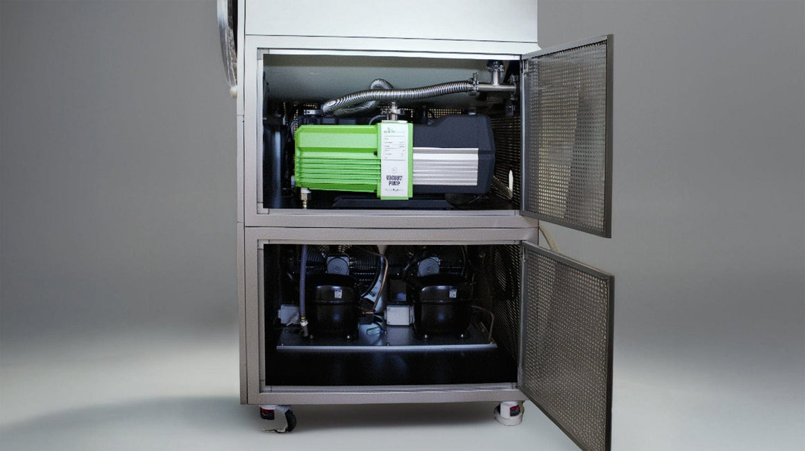Green vacuum pump and two black compressors inside commercial freeze dryer.