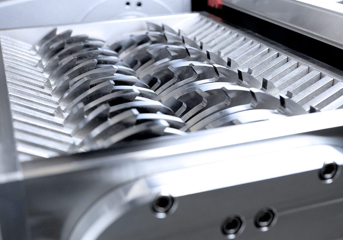 Close-up of a heavy-duty industrial shredder with sharp, interlocking metal blades.