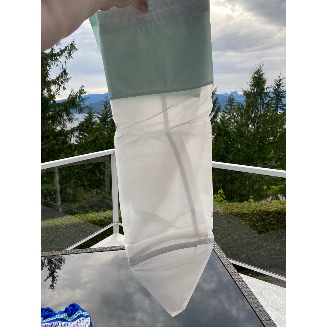 Translucent white and green bubble replacement bag with conical bottom, held on a balcony with lake and mountains.